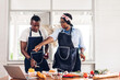 © Art_Photo - Portrait of love african american couple having fun cooking together and looking for recipe on Internet with laptop computer to prepare the yummy eating in kitchen at home