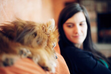Girl Sits Close To Her Ginger Pomeranian Dog On A Sofa