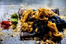 Famous Kanda Bhaji Or Kanda Bhajiya Or Kanda Pakora In A Container On A Black Surface Along With Chickpea Flour, Spices, And All Other Ingredients For Making It. Horizontal Shot.