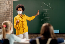 Black Teacher Wearing Face Mask While Explaining Math Lesson In The Classroom.