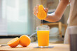 Woman hand squeezes juice from fresh orange, Homemade a glass of orange juice