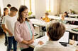 © Drazen - Happy schoolgirl and her classmates taking test results from teacher in the classroom.