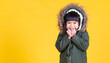 © paulaphoto - Portrait of young happy little asian girl wearing fur hooded winter coat sweater isolated on yellow background with copy space. Education childhood lifestyle, winter cold banner
