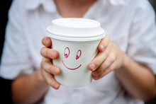 Hands Holding Paper Drinking Cup With Smiley Face Drawn On