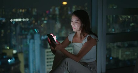 Sticker - Woman use of mobile phone and sit beside window with city view at night