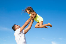 Joyful Dad Holding Excited Girl And Throwing Hands Up In Air. Handsome Father And Little Daughter Having Fun Outdoors, Playing Active Games. Family Outdoor Activities Concept
