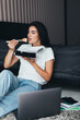 © F8  \ Suport Ukraine - Young woman eating sushi look at her laptop sitting on the floor at bed working at home
