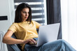 © F8  \ Suport Ukraine - Young smiling woman is sitting on modern chair at home working on laptop in relaxing atmosphere