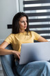 © F8  \ Suport Ukraine - Young smiling woman is sitting on modern chair at home working on laptop in relaxing atmosphere