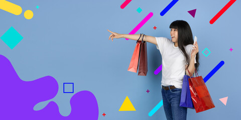 Wall Mural - Pointing with shopping bags. Asian woman's portrait. Beautiful female model in casual. Concept of human emotions, facial expression, sales, ad, copyspace. Bright, modern illustrated background.