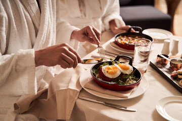 Two people in bathrobes eating at the table in hotel