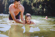 © Rob and Julia Campbell/Stocksy - Young dad teaching little girl how to swim at lake in summer