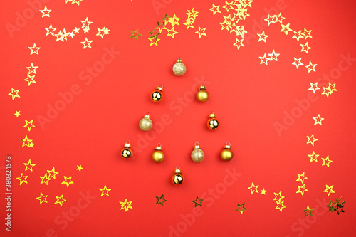 Fotografía christmas tree made of ball decoration on red background with golden confetti stars