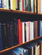 © Rialto Images/Stocksy - Rows of stacked books on book shelf, blurred focus