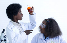 Dark-skinned Boy And Girl  Interested  Experimenting With Chemistry At The Lab, With An Excited Face, Boy Raised A Beaker To Look At, Selective Focus
