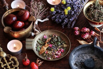 Wiccan witch altar with herb blend mix in brass dish, ready for incense burning. Background filled with dried lavender rose flowers, herbs, plants, chestnuts, burning candles. Incense burning ceremony