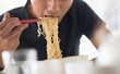 © Tetra Images - Man eating noodles with chopsticks