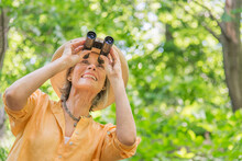 Senior Woman With Binoculars In Park