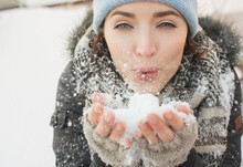 Woman Blowing Snow Towards Camera