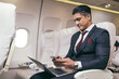 © winnievinzence - Male passenger business man using smartphone checking work or news on airplane cabin. wireless technology and remotely working. social network and connection. travel to work abroad concept.