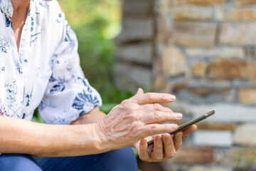 Crop view of elderly woman hands holding a smartphone