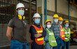 © visoot - Industrial workers wearing safety mask to protect for pollution and virus standing in a large industrial factory.