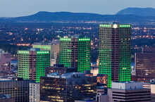 Three Skyscrapers Illuminated With Green Light Towering Over Cityscape