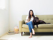 © Jessica Peterson/Tetra Images - Portrait of woman with dog sitting on sofa