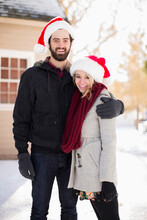 Portrait Of Young Couple In Santa Hats In Front Of House