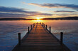 © DERMOT CONLAN/Tetra Images - Symmetrical view of jetty on frozen lake, hills in background at sunrise