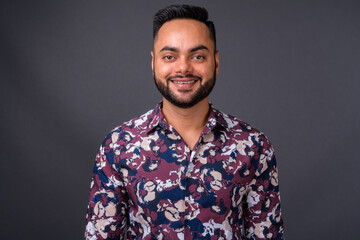 Young bearded Indian man against gray background