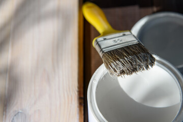 White paint and brush. Painting a textured wooden board.