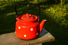 Red Kettle In White Dots On A Background Of Grass