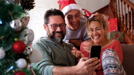 Wall Mural - Happy caucasian family at home celebrating together Christmas Eve day with joy and love - concept of video call conference with friends and parents with internet connection - mother father and son