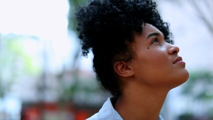 hopeful brazilian woman looking up to sky, portrait face