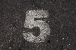 © MyMicrostock/Stocksy - Number 5 Printed on White Over Dirty Asphalt