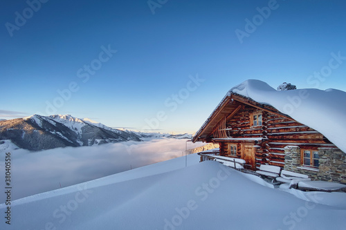 Cuadros en Lienzo Snow covered mountain hut old farmhouse in the Austrian alps at sunrise against blue sky