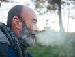 © Martin Matej/Stocksy - Old bearded man smoking a cigarette outside