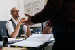 © VegterFoto/Stocksy - Serious businessman looking at colleague gesturing at desk