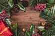 © Tatyana - Christmas frame made of fir tree and magonia branches,golden apples,cones,red viburnum berries and red gift box on the dark wooden rustic background.Christmas background.Copy space for text, top view.