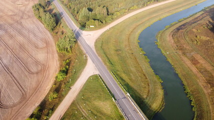 Top view of asphalt road bridge over the river in the fields