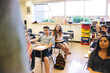 © Rob and Julia Campbell/Stocksy - Real high school teenage students listening to teacher and learning together in classroom