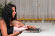 © Silvia  - Mujer morena sentada con bebé tecleando en un ordenador portátil