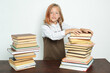 © Dzmitry - A teenage girl takes books from a stack of books on the table.