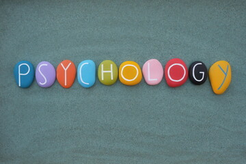 Psychology text composed with multicolored stone letters over green sand