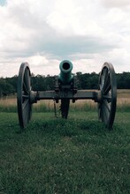 An Old Antique Historic Civil War Cannon In A Field Of Green Grass And Blue Skies Overhead