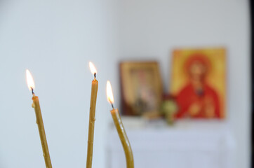 Wall Mural - Candles in front of icons in the Orthodox church. A burning wax candles, cross and icons in monastery. Christian religion. Altar in church decorated for Christmas.