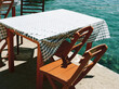 © Kirstin Mckee/Stocksy - Table and chairs in harbour, Greece
