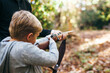 © Kelly Knox/Stocksy - father and son shooting a rifle in the forest