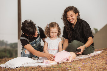 Wall Mural - couple of women having fun with daughter outdoors